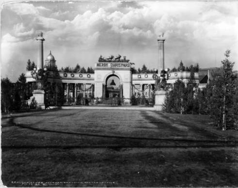 Christmas decorations on Voorhies Memorial, Denver Civic Center, Colorado, include Santa Claus and reindeer on top of arch, wreaths and garland on colonnade, and bell in center of arch; Christmas trees are alongside walkways. (1923)