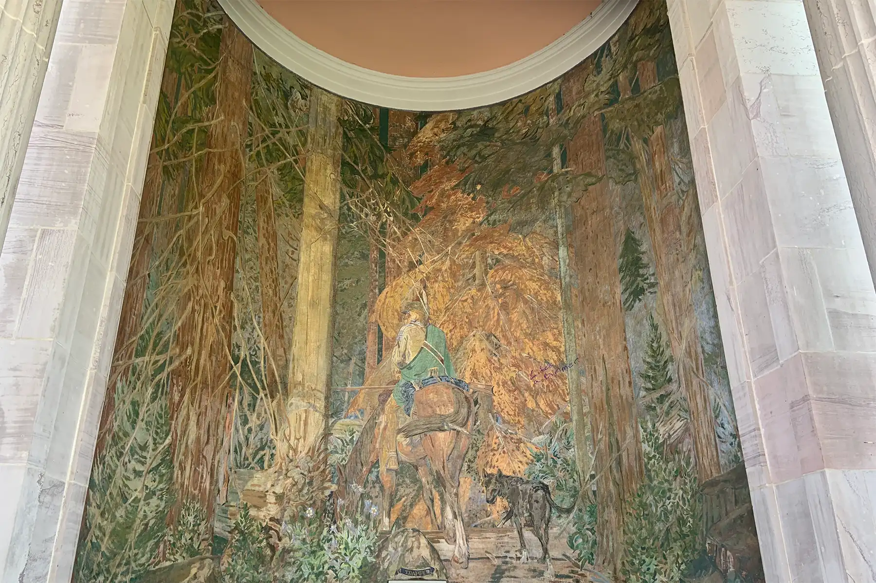 the-trapper-allen-true Painting in greens, browns, and gold features a man riding a horse away from us, while turning to look back at the viewer.